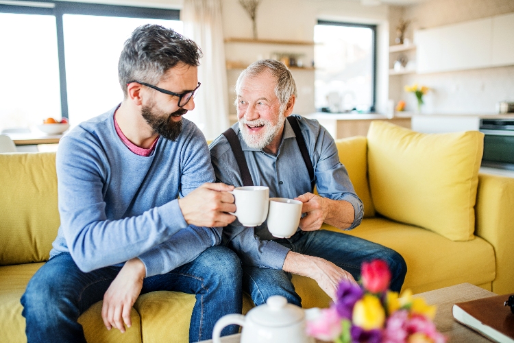 Dad and son drinking tea on yellow sofa