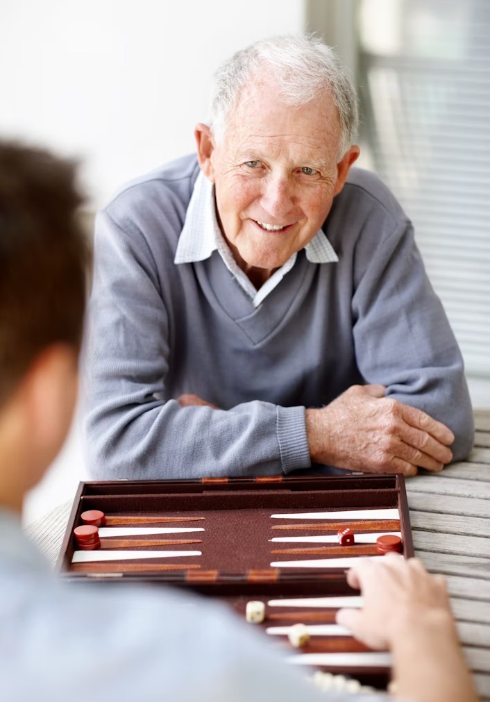 older man smiling at someone over a board game