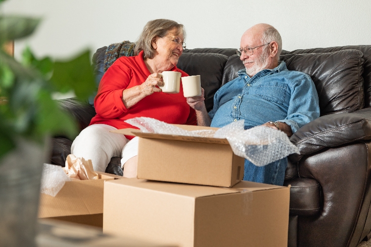 Senior couple on sofa with moving boxes around them