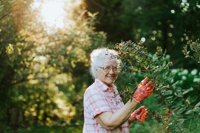 elderly woman smiling at camera whilst gardening