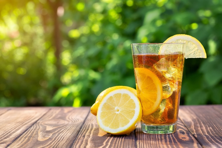 A glass of ice tea with lemons on a wooden table